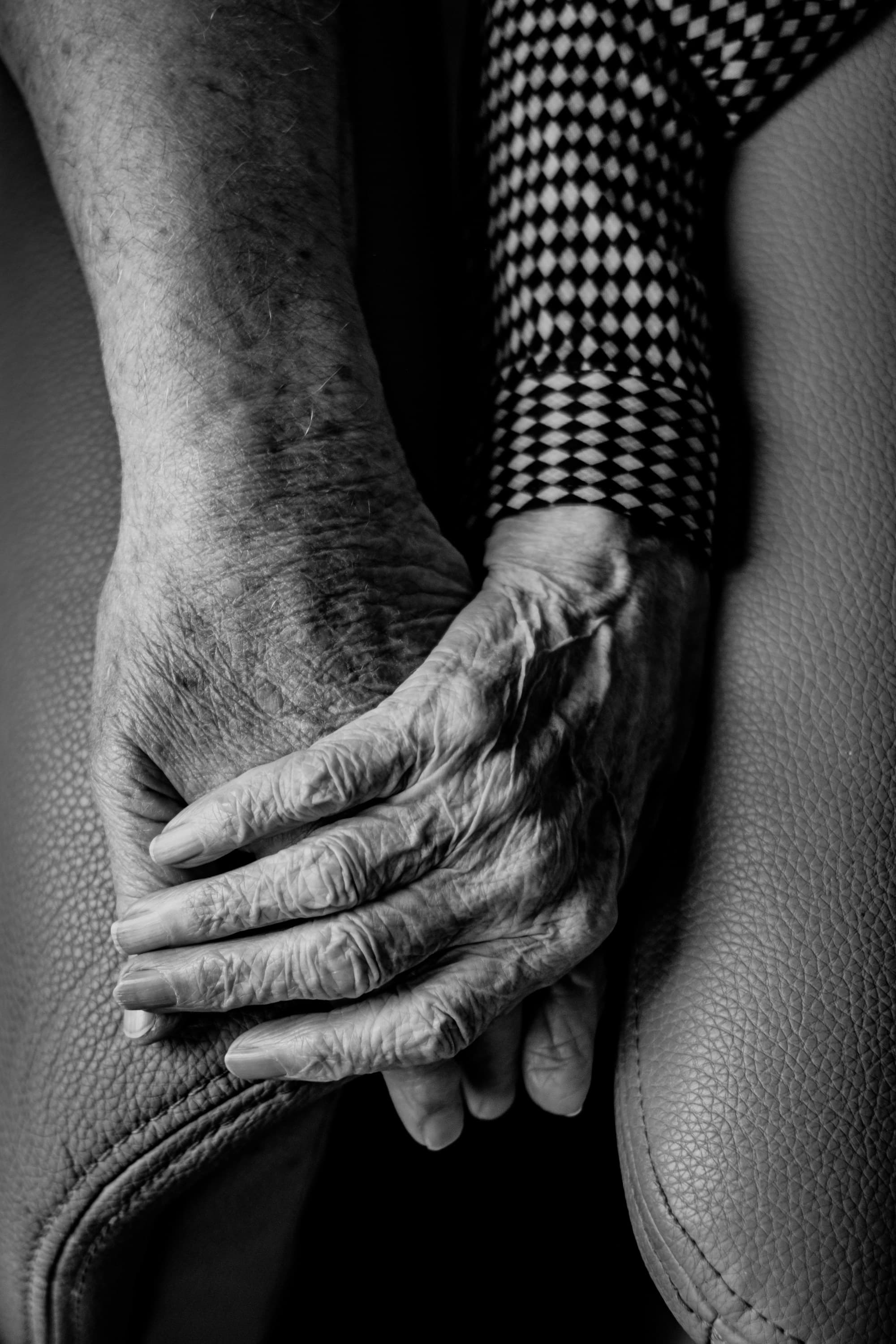 Close black-and-white photograph of an older person’s hands resting together.
