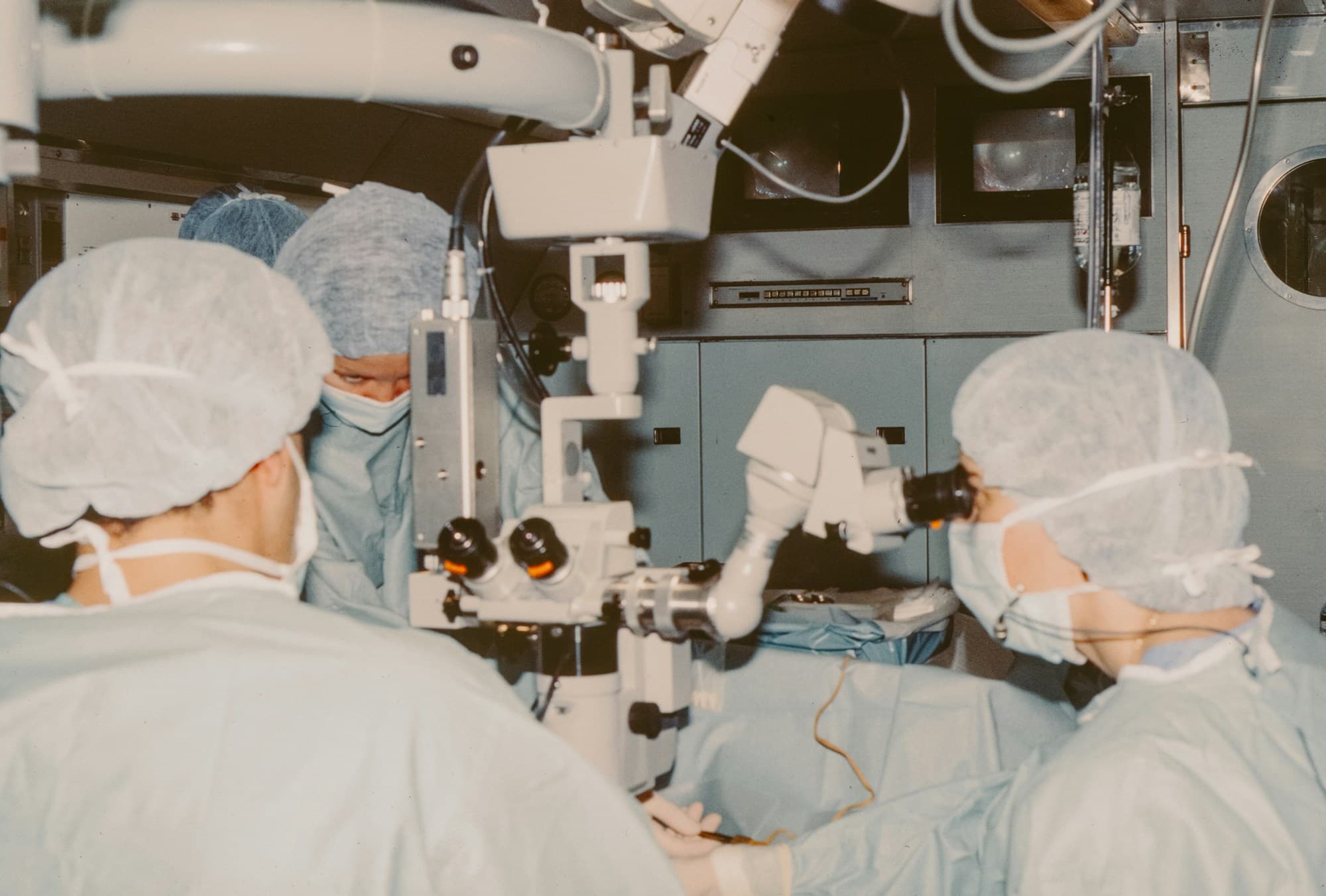 A surgical team working through an operating microscope in a theatre.
